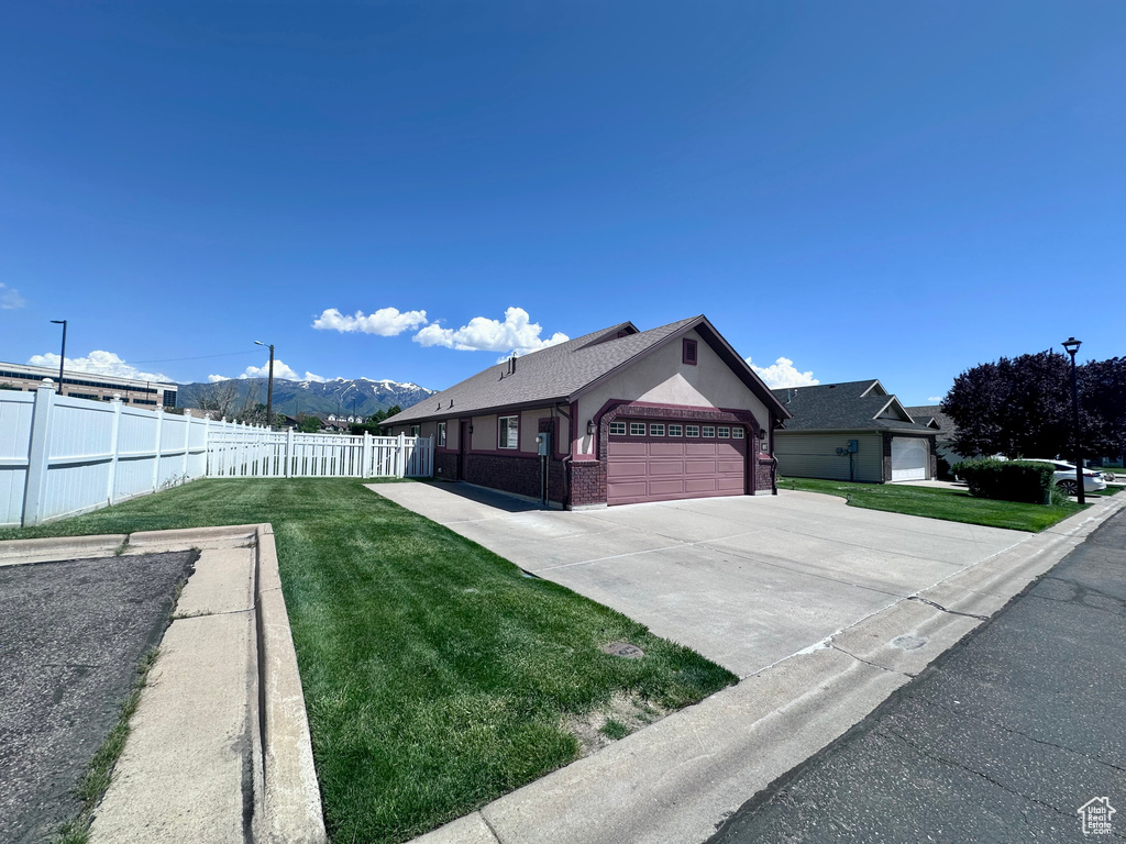 View of home's exterior featuring an attached garage, concrete driveway, a mountain view, and brick siding