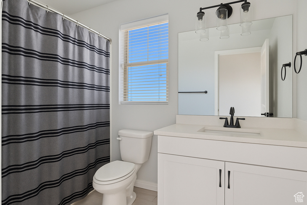 Bathroom featuring toilet, vanity, baseboards, and a shower with shower curtain