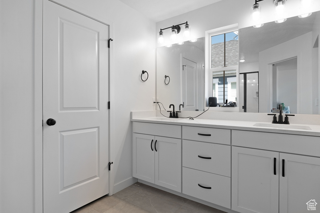 Bathroom with double vanity, baseboards, and tile patterned flooring