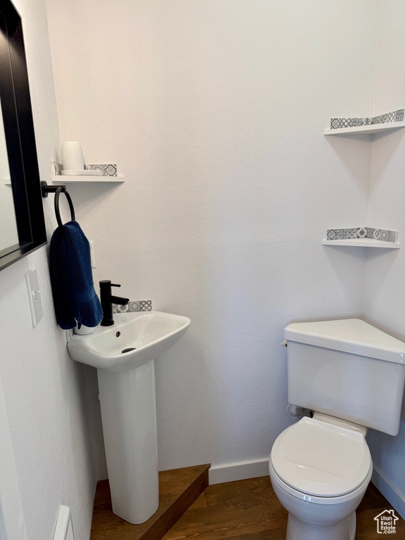 Bathroom with baseboards, toilet, and wood finished floors