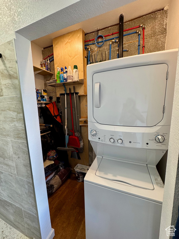 Laundry area with stacked washer / drying machine and dark wood-style floors