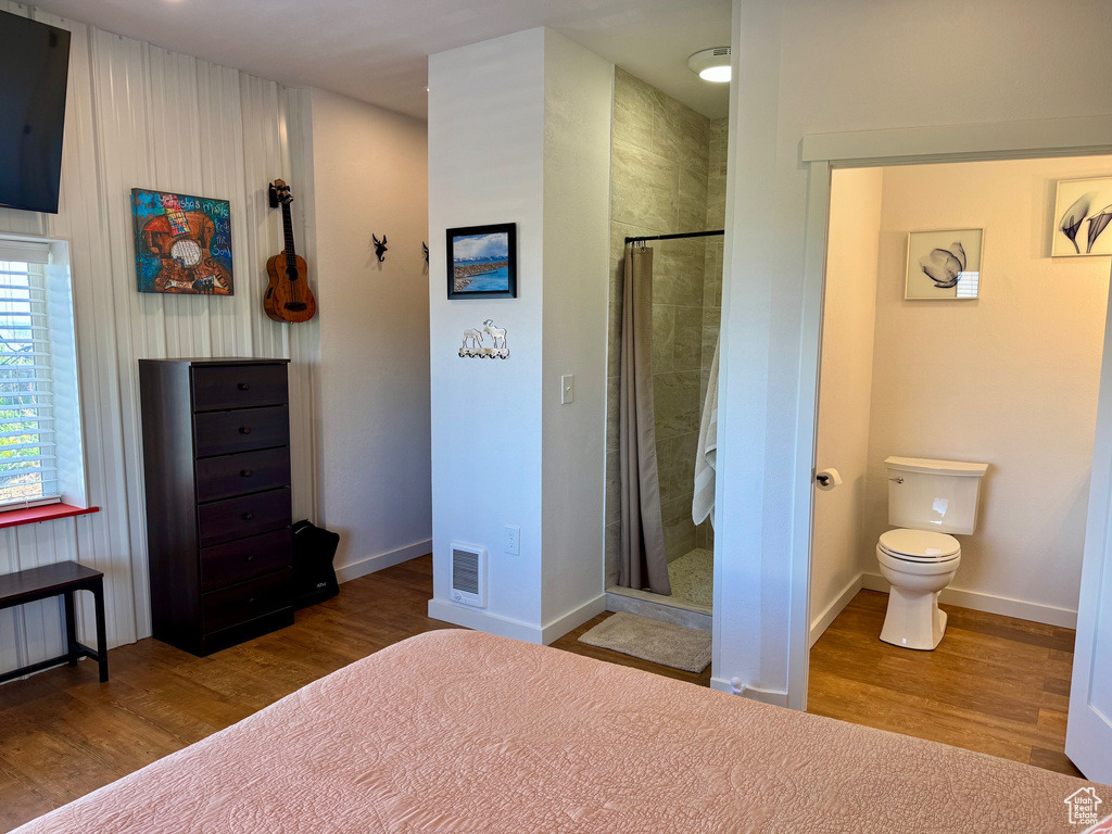 Bedroom featuring wood finished floors, baseboards, and ensuite bathroom