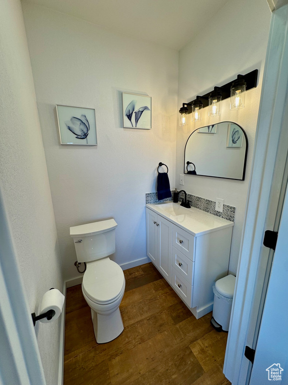 Bathroom with toilet, wood finished floors, vanity, and baseboards