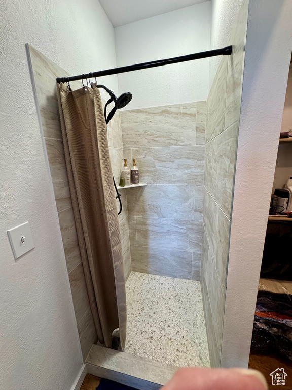Full bathroom featuring a stall shower and a textured wall