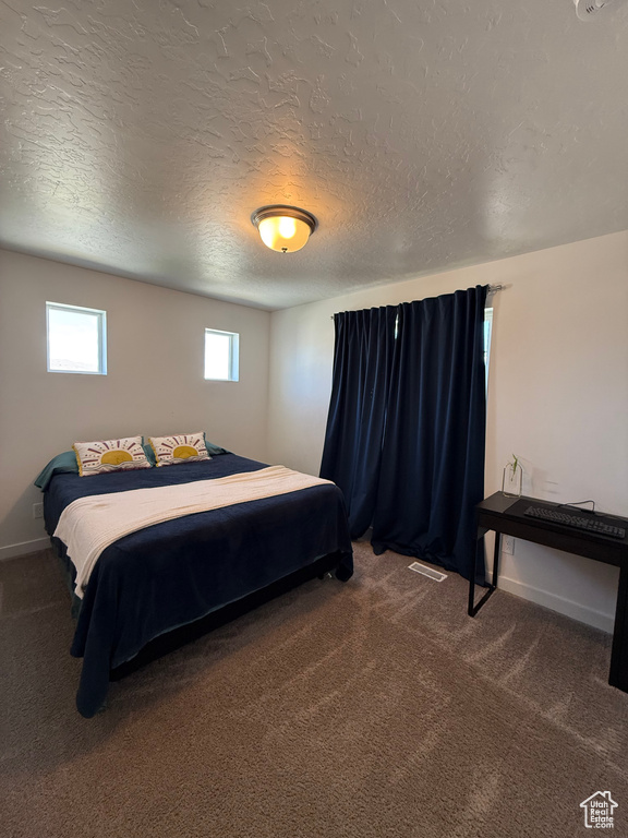 Bedroom with carpet floors, a textured ceiling, and baseboards