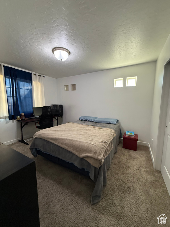 Carpeted bedroom featuring a textured ceiling and baseboards