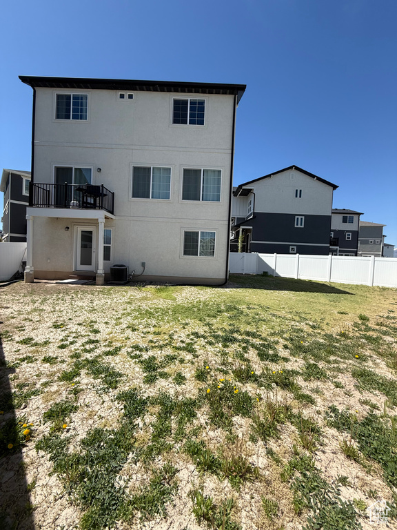 Back of house featuring central AC unit, a balcony, and stucco siding