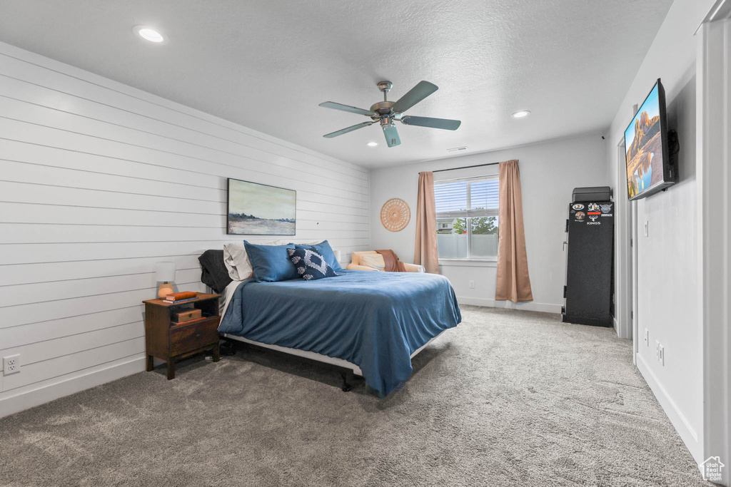 Carpeted bedroom featuring recessed lighting, wooden walls, a textured ceiling, and ceiling fan