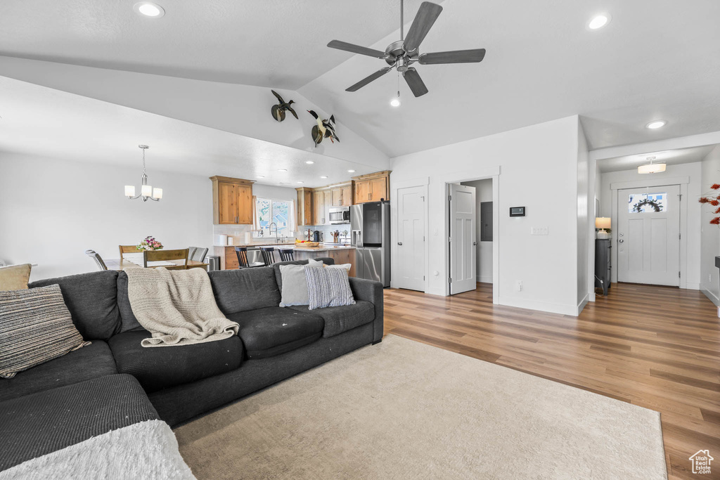 Living room with a chandelier, light wood-type flooring, ceiling fan, recessed lighting, and lofted ceiling