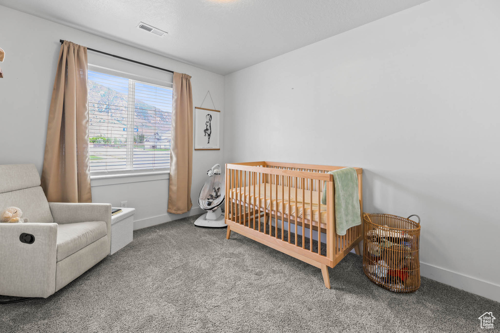 Bedroom featuring carpet floors, a crib, and baseboards