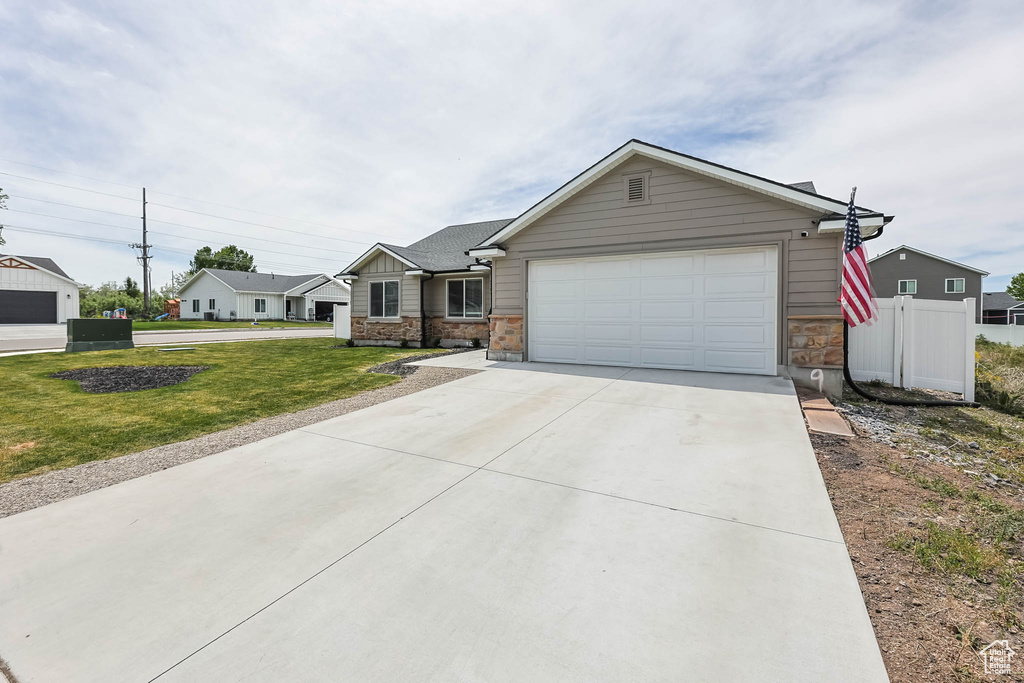 Single story home with concrete driveway, stone siding, and an attached garage