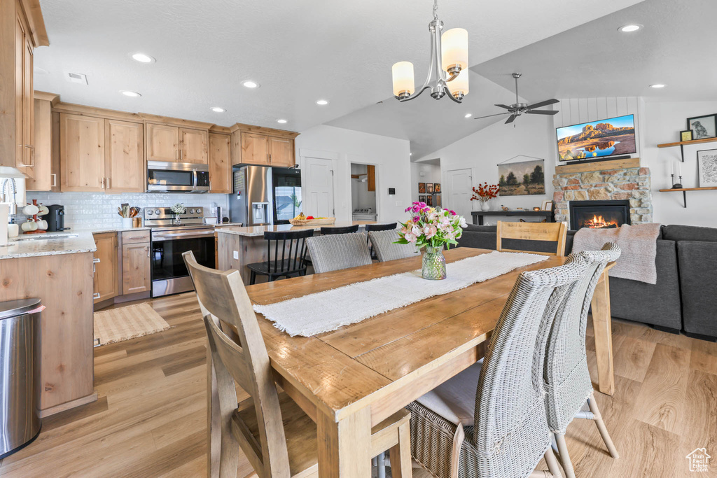 Dining room featuring a ceiling fan, light wood-type flooring, a fireplace, recessed lighting, and lofted ceiling