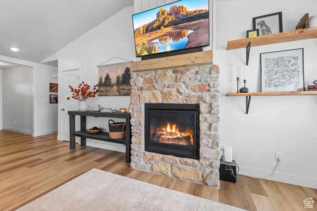 Living area with a fireplace, vaulted ceiling, baseboards, wood finished floors, and recessed lighting