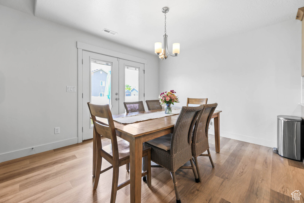 Dining area featuring a chandelier, light wood-style flooring, french doors, and baseboards