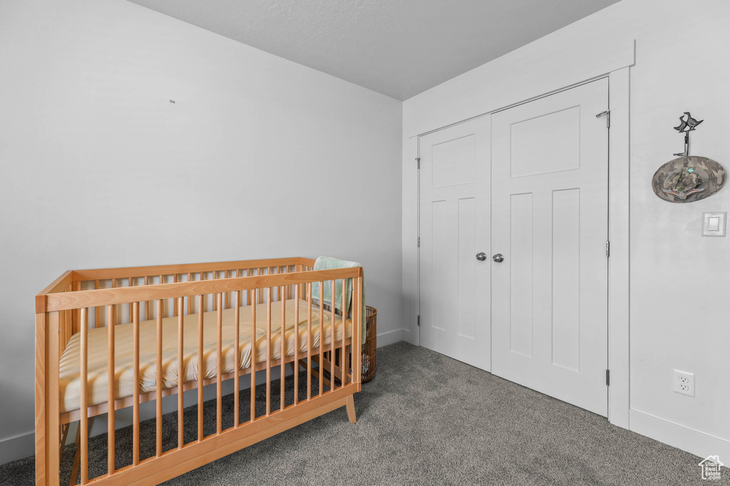 Bedroom featuring carpet floors, a closet, baseboards, and a crib