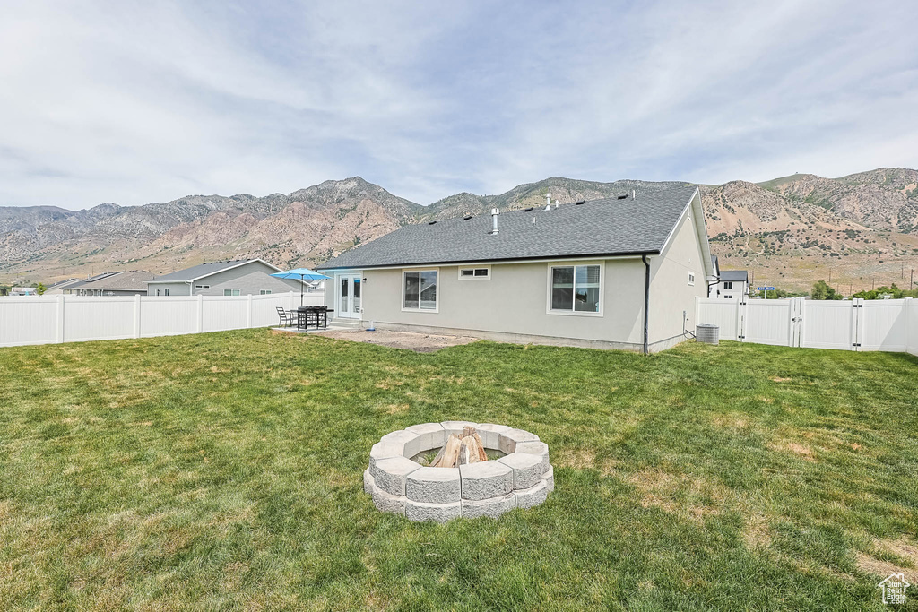 Back of property featuring an outdoor fire pit, a patio area, a mountain view, and a gate