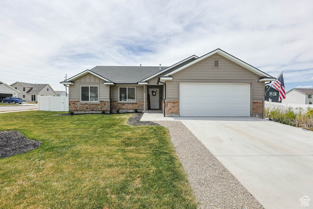 View of front of house with an attached garage, driveway, stone siding, and board and batten siding