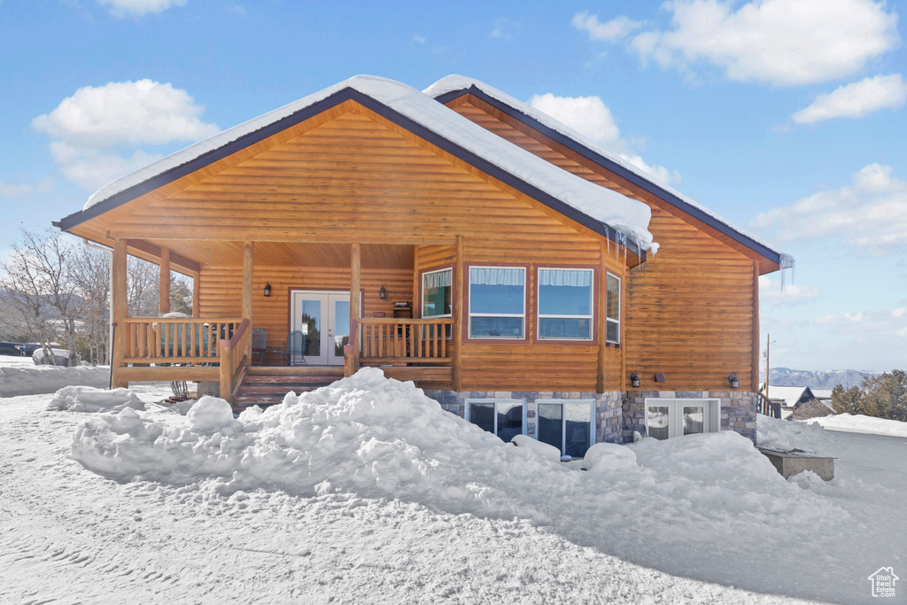 Snow covered back of property with french doors