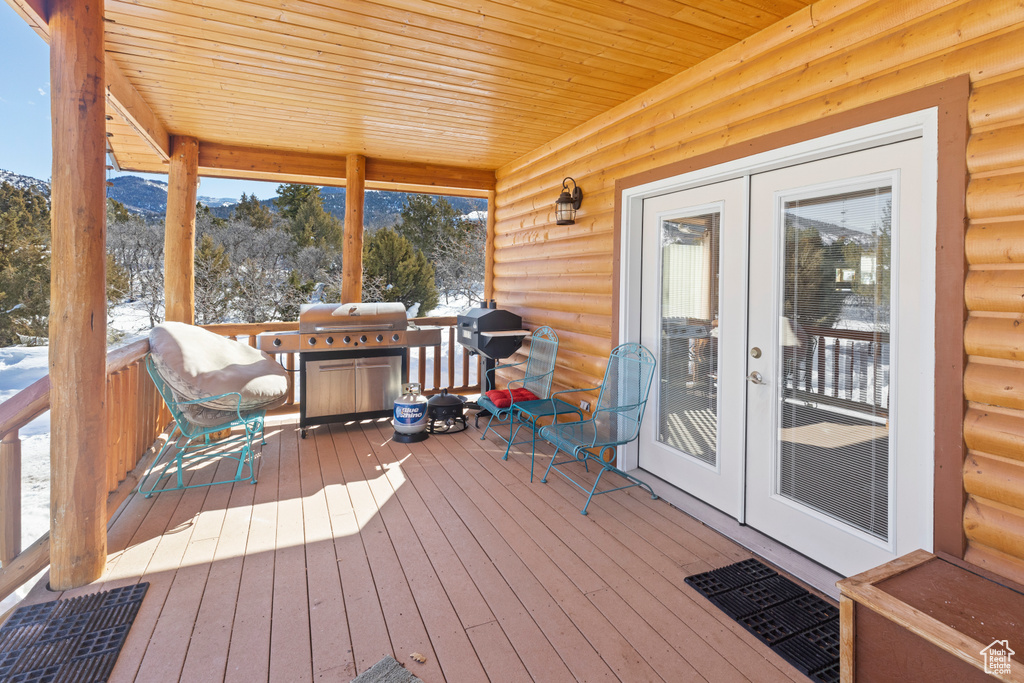 Wooden terrace with grilling area, french doors, and a mountain view