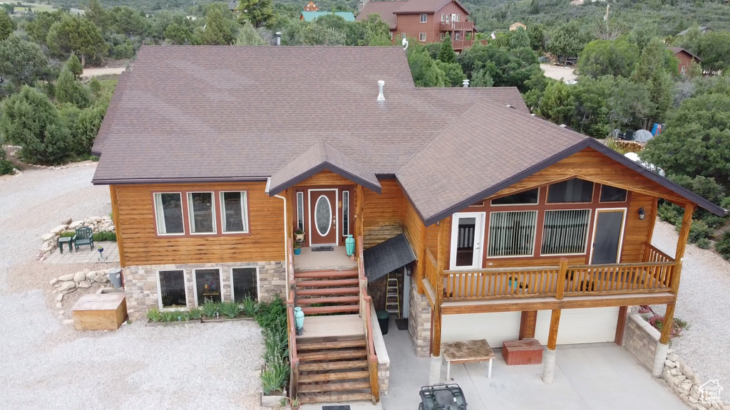 Chalet / cabin with stone siding, concrete driveway, an attached garage, and roof with shingles