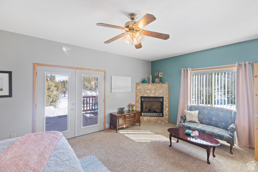 Carpeted bedroom featuring access to exterior, french doors, a ceiling fan, and a fireplace
