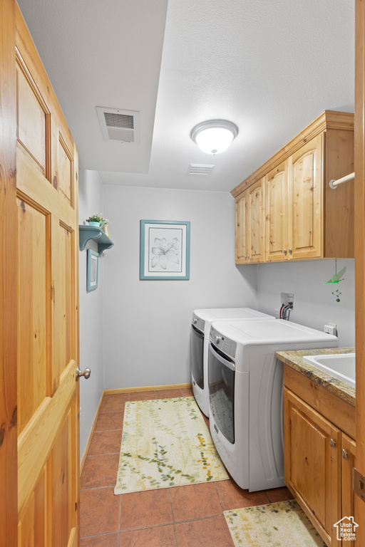 Laundry area featuring washer and dryer, cabinet space, light tile patterned flooring, and baseboards
