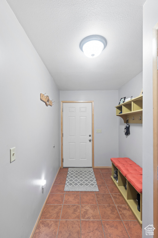 Mudroom featuring a textured ceiling, tile patterned floors, and baseboards