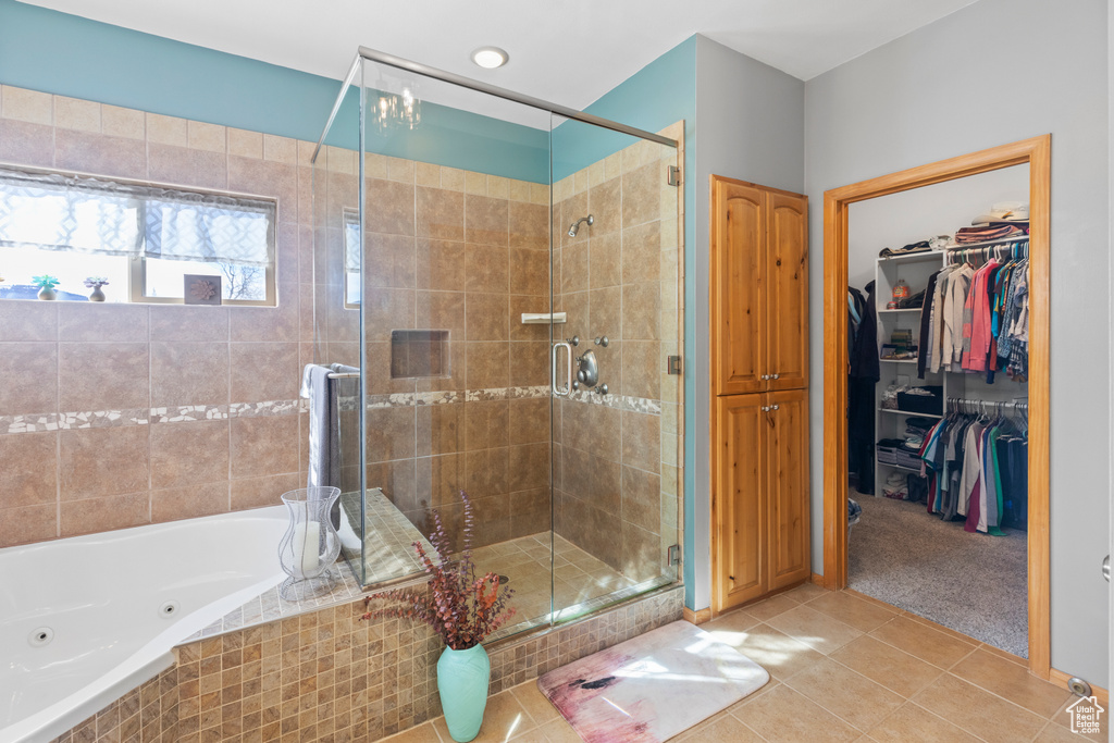 Full bath featuring tile patterned flooring, a shower stall, a jetted tub, and a spacious closet