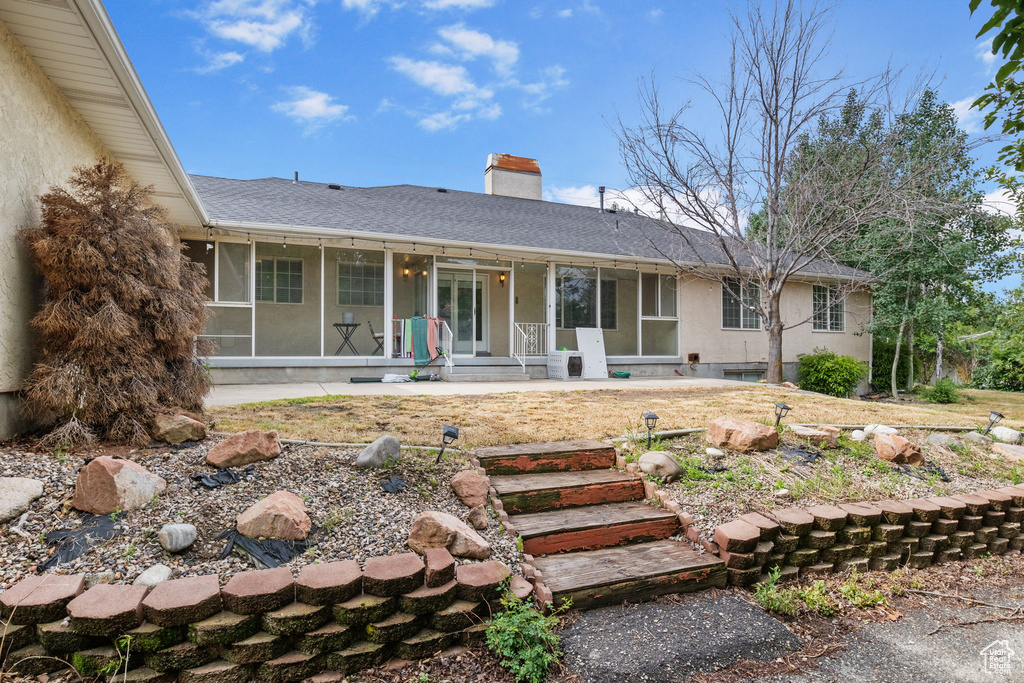 View of front of house featuring a chimney, roof with shingles, stucco siding, and covered porch