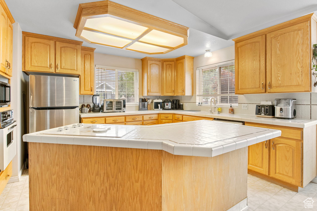 Kitchen featuring appliances with stainless steel finishes, healthy amount of natural light, decorative backsplash, and a sink