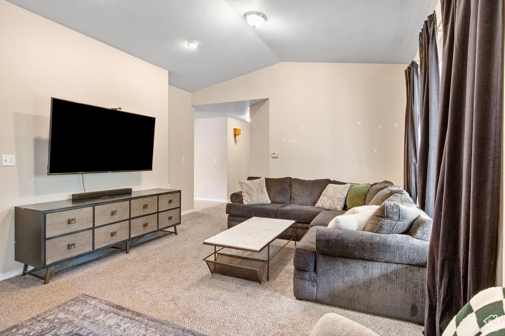 Carpeted living area featuring lofted ceiling and baseboards
