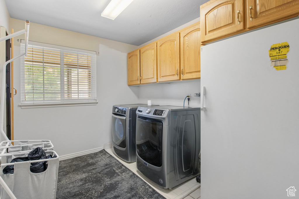 Laundry area featuring cabinet space, separate washer and dryer, tile patterned floors, and baseboards