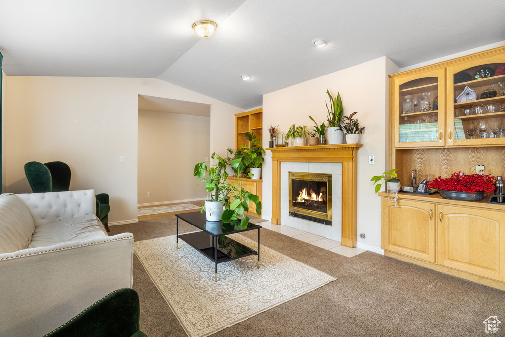 Living area featuring light colored carpet, a tile fireplace, lofted ceiling, bar area, and baseboards