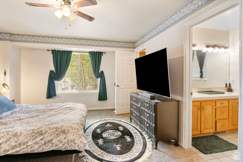Bedroom with ensuite bath, light tile patterned floors, a ceiling fan, and baseboards
