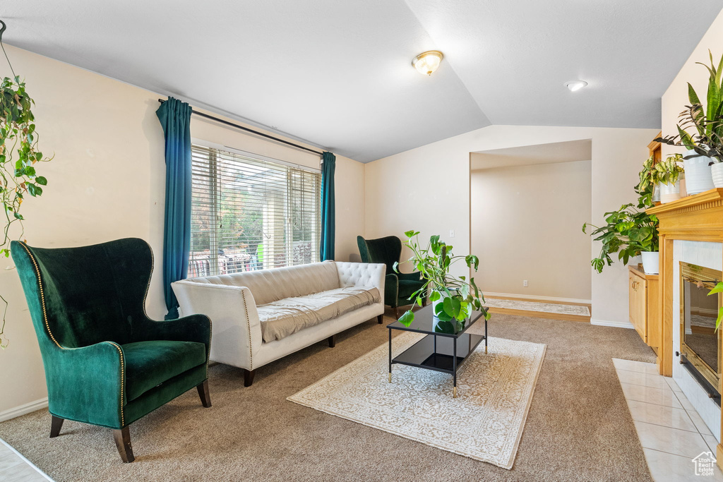 Living room with lofted ceiling, light colored carpet, baseboards, and a tile fireplace