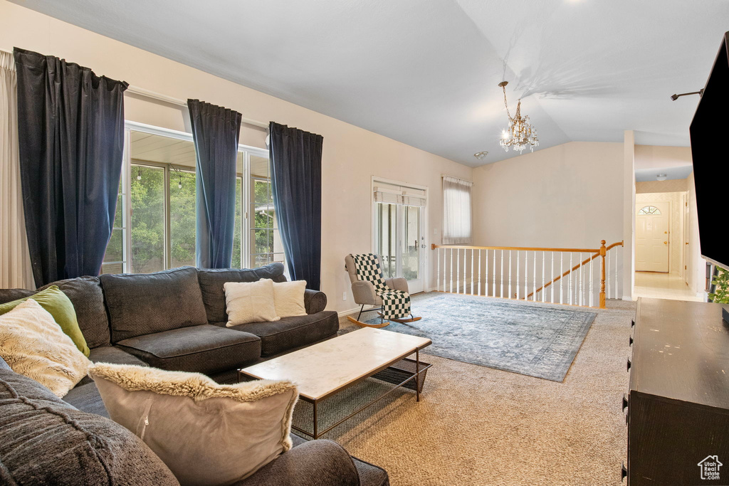 Living room featuring lofted ceiling, a chandelier, and carpet floors
