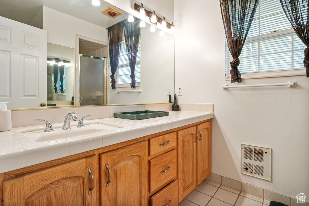 Full bath featuring tile patterned flooring, plenty of natural light, double vanity, and a stall shower