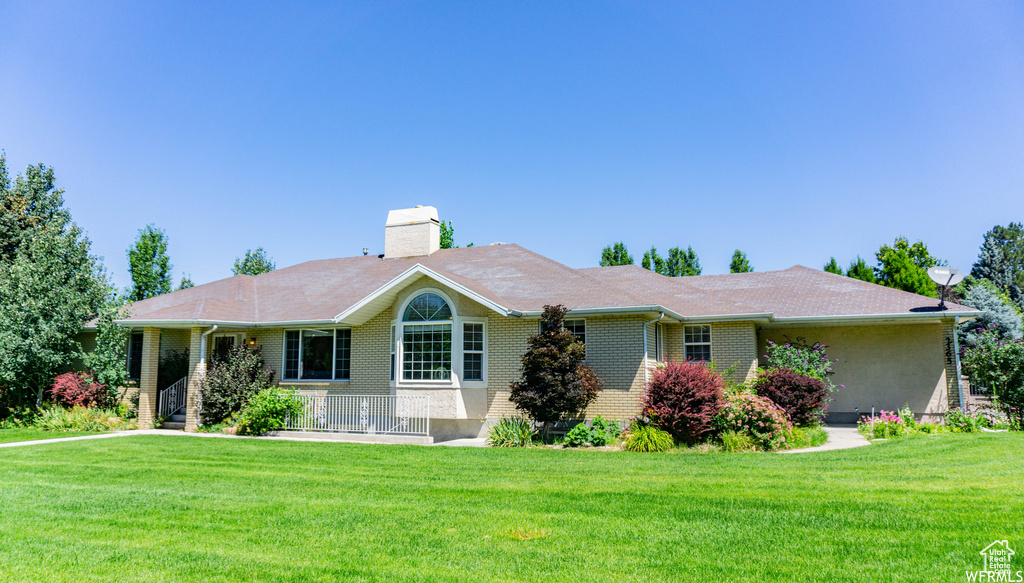 Ranch-style home featuring brick siding, a chimney, and a front yard