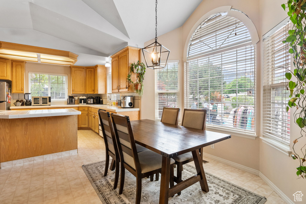 Dining area with lofted ceiling, a chandelier, and baseboards