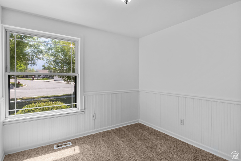 Carpeted spare room featuring wainscoting
