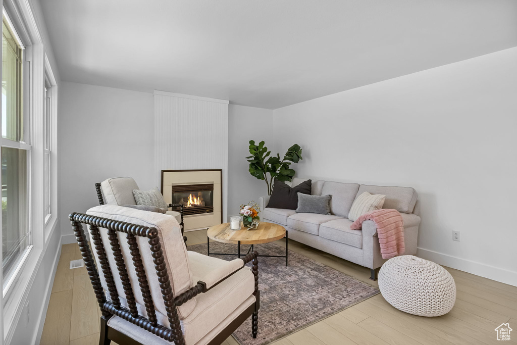 Living room with wood finished floors, a glass covered fireplace, and baseboards
