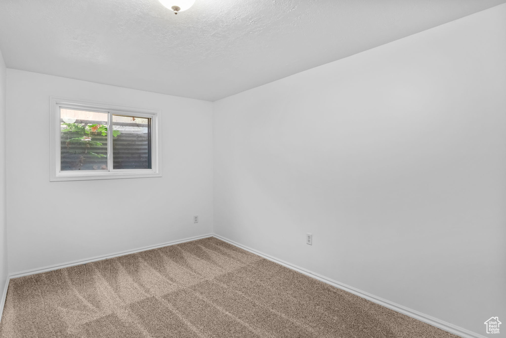 Empty room with carpet floors, baseboards, and a textured ceiling