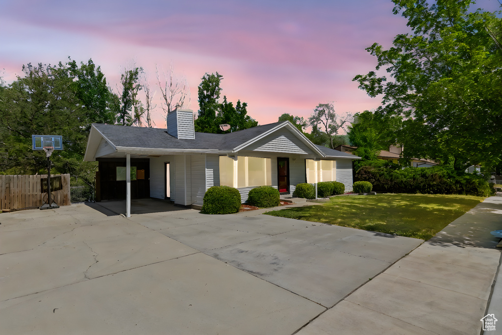 Single story home with concrete driveway, a carport, and a chimney