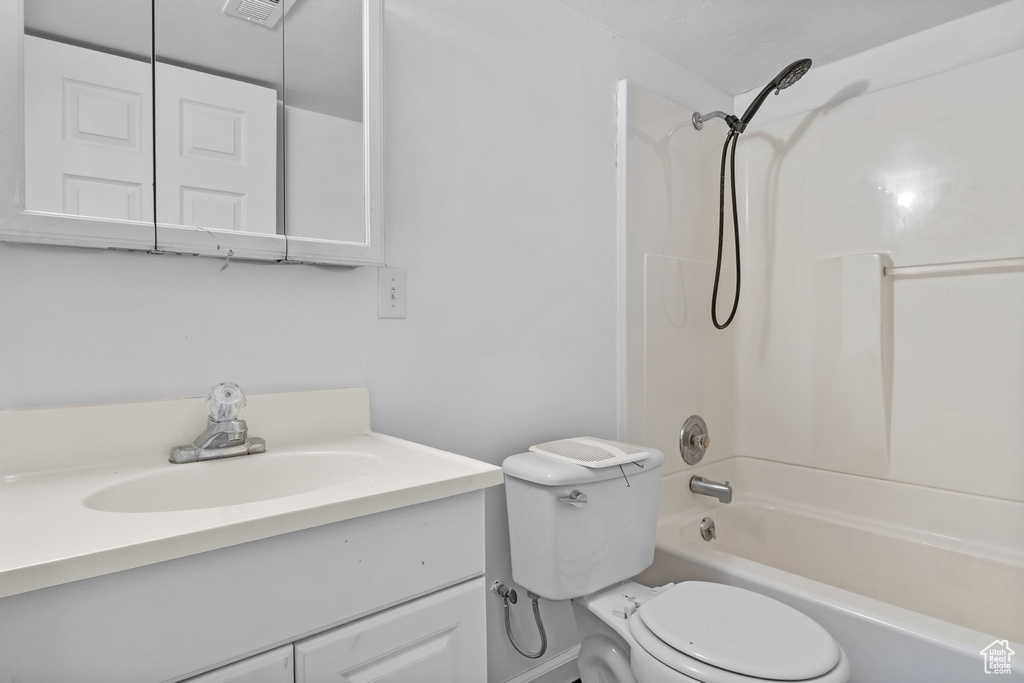 Bathroom featuring toilet, vanity, and shower / tub combination