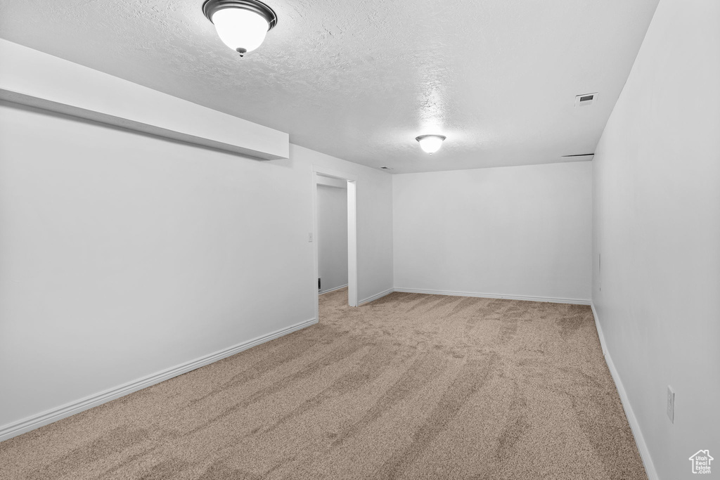 Carpeted empty room featuring a textured ceiling and baseboards