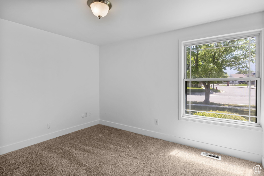 Spare room featuring carpet flooring and baseboards