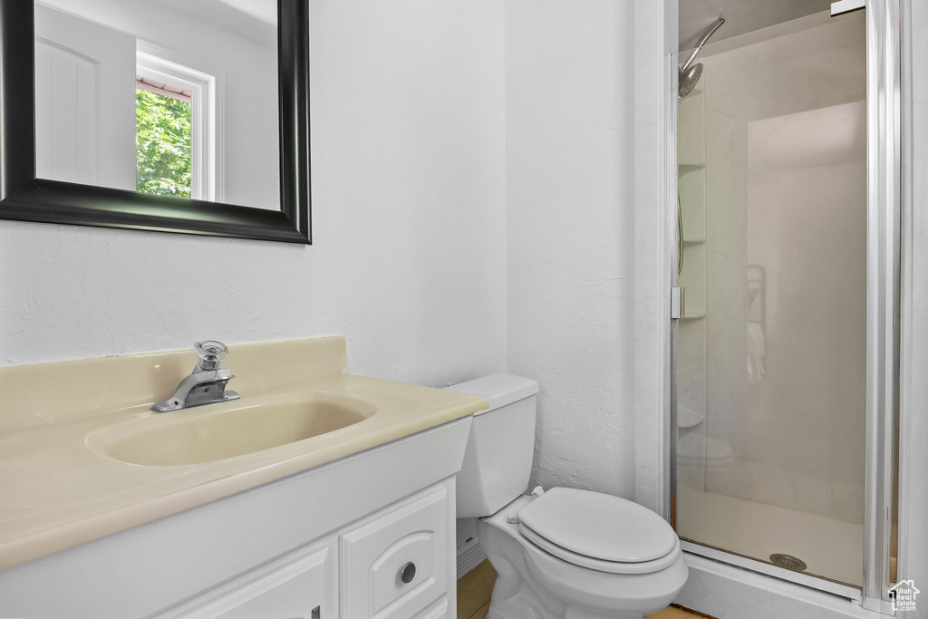 Full bathroom with vanity, a shower stall, toilet, and a textured wall