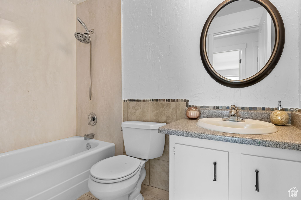 Bathroom with vanity, toilet, bathtub / shower combination, tile walls, and tile patterned flooring