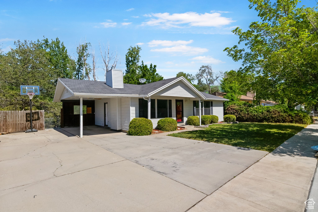 Ranch-style home featuring concrete driveway, a carport, and a chimney