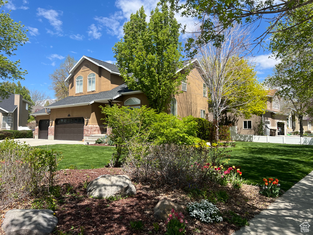 Obstructed view of property with stucco siding, stone siding, an attached garage, and driveway